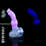Fantasy silicone werewolf dildo in the Epic colourway, showing a soft pink and lavender shaft with metallic silver base in natural light, alongside a deep blue glowing version displayed in darkness.