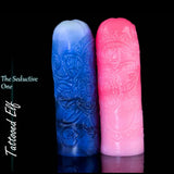 Two upright Tattooed Elf silicone masturbators in pink and blue-white colourways, showing their ornate fantasy tattoo designs