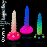 Godemiché Orwyn Unicorn Shape-Shifting Druid en coloris Legendary réactif à la lumière, présenté en lumière naturelle, sous lumière noire et dans l’obscurité complète pour montrer son effet lumineux.